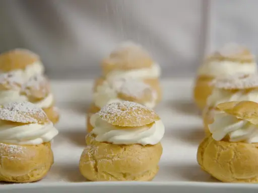 Petits choux garnis de crème fouettée, saupoudrés de sucre glace. La cuisson des choux est parfaite, dorée et légère.