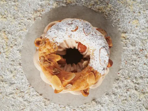 Un Paris-Brest aérien, garni d'une crème onctueuse et décoré d'amandes effilées. Le praliné pour Paris-Brest est ici sublimé.
