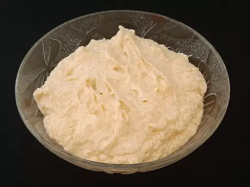 Crème d'amande onctueuse dans un bol en verre texturé, prête à être dégustée.
