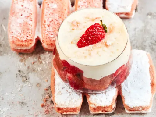 Un délicieux tiramisu aux biscuits roses de Reims, garni de fraises et de crème onctueuse, sur un lit de biscuits saupoudrés de sucre glace.