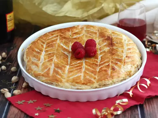 Une délicieuse galette pistache framboise dorée, décorée de fruits rouges frais, prête à être dégustée.