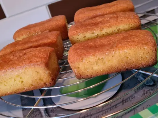 Six financiers dorés, des quatre quarts sans œuf, refroidissent sur une grille.