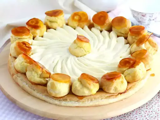Un magnifique gâteau Saint-Honoré, orné de choux caramélisés et d'une crème onctueuse, prêt à être dégusté.
