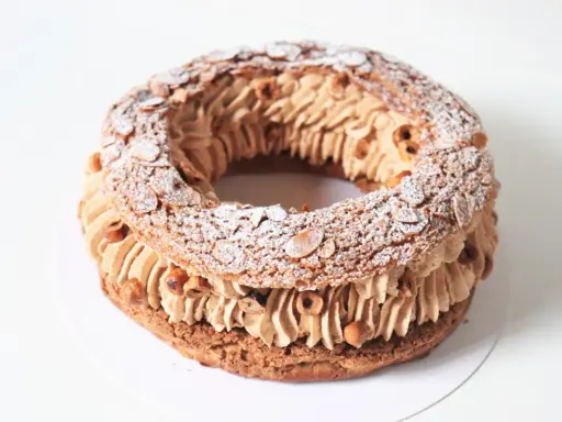 Un Paris Brest meilleur du chef, généreusement garni de crème pralinée et parsemé d'amandes effilées et de noisettes.
