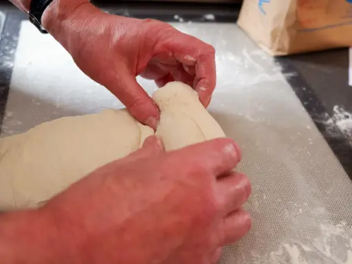 Mains travaillant la pâte à pain, étape d'autolyse. La pâte est souple et prête à être façonnée.