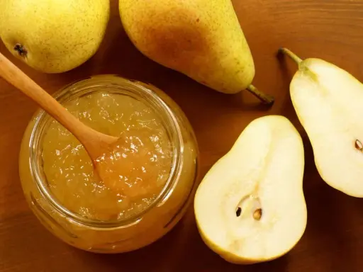 Un pot de confiture de poires maison, avec une cuillère en bois, entouré de poires fraîches coupées et entières sur fond de bois.