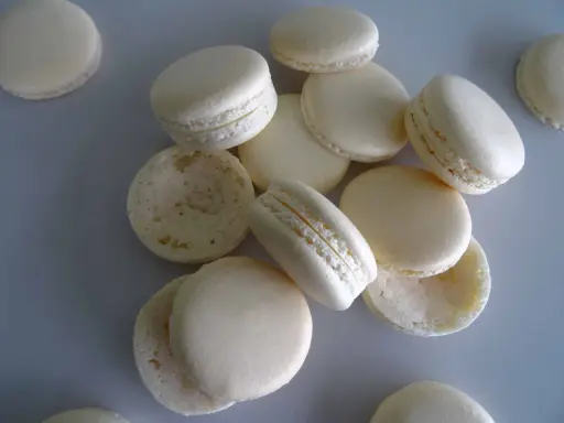 Des macarons blancs, certains assemblés, d'autres séparés, prêts pour la cuisson macaron chaleur tournante.