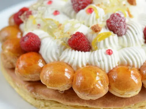 Un déliceux saint honoré framboise, orné de crème fouettée, de fruits rouges et de petites brioches caramélisées.