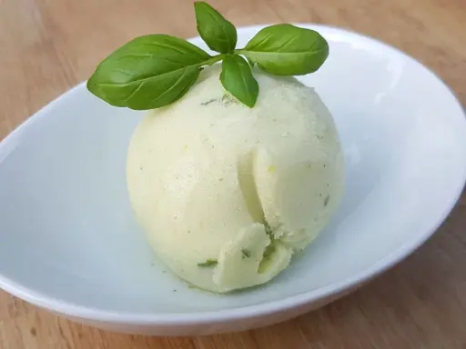 Une boule de sorbet citron vert et basilic, parfaite pour une recette sorbet citron professionnel. Délicatement garnie de feuilles de basilic frais.