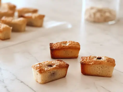 Financiers dorés, parfaits après une cuisson à chaleur tournante. Ils sont garnis de fruits et de noix de coco râpée.