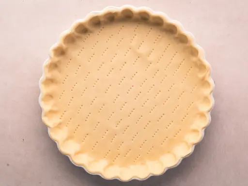 Pâte brisée salée prête à être garnie. Les petits trous préparent la base pour une cuisson parfaite.