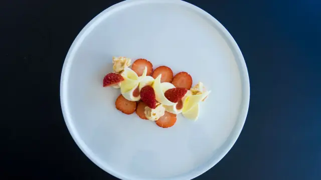 Délicieux dessert fraise melba, composé de fraises fraîches, de crème onctueuse et de copeaux de chocolat blanc, le tout présenté sur une assiette blanche.