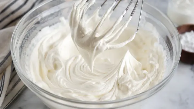Crème fouettée onctueuse dans un bol en verre, prête à être utilisée. La question quelle crème pour chantilly est résolue !