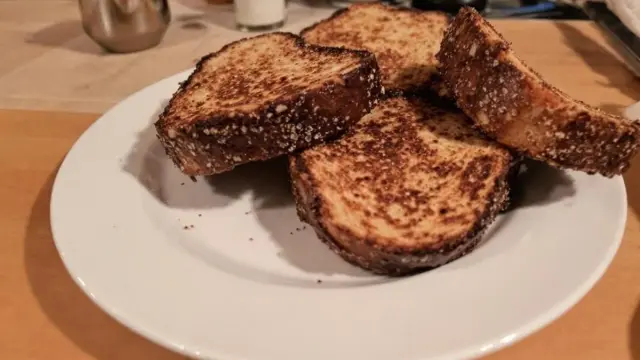 Quatre tranches de pain dur au four, dorées et croustillantes, sur une assiette blanche.