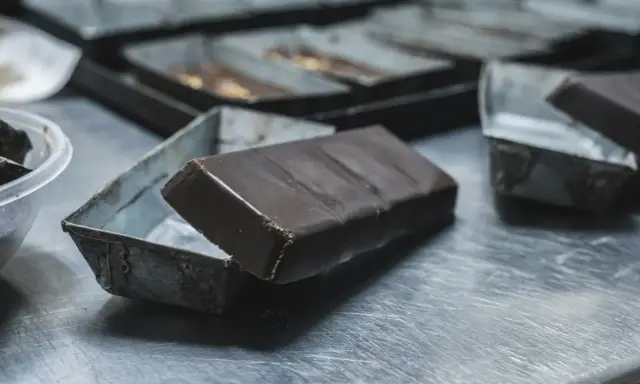 Une tablette de chocolat posée sur une petite boîte métallique. Idéal pour apprendre comment faire des copeaux de chocolat.
