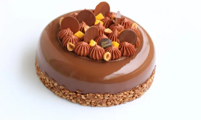 Entremet au chocolat avec un biscuit croustillant pour entremet, garni de rochers chocolatés, noisettes et dés de mangue.