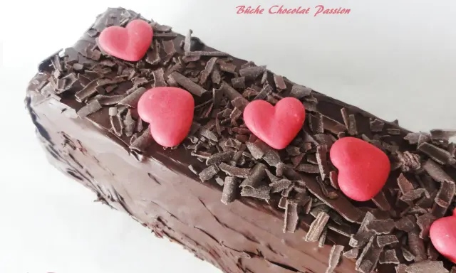 Bûche chocolat passion, un délice chocolaté orné de copeaux de chocolat et de cœurs rouges.