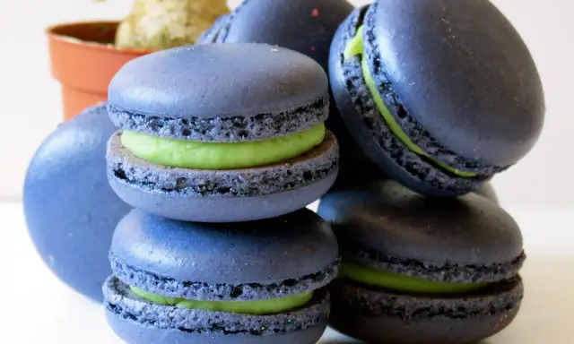 Macarons bleus avec une garniture verte vibrante, parfaits pour une recette macaron pistache.