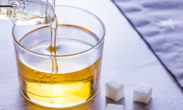 Versez le sirop de glucose dans un bol. Une recette simple pour des desserts parfaits. Trois morceaux de sucre à côté.