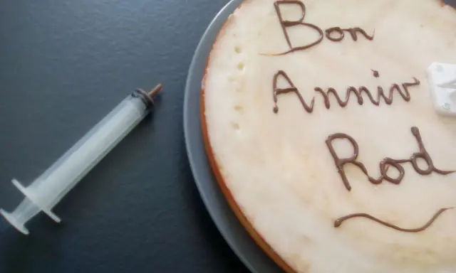 Glaçage pour écrire sur un gâteau : "Bon Anniv Rod". Une seringue est à côté, prête pour la décoration.