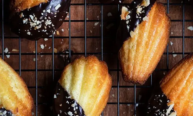 Des biscuits madeleine au chocolat, parsemés d'éclats d'amandes, refroidissent sur une grille. Un délice gourmand !