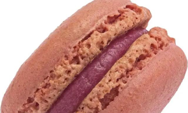Un délicieux macaron framboise, avec sa coque rose pâle et sa ganache violette intense.
