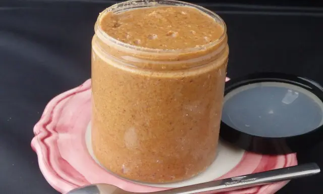 Un pot de praliné maison, onctueux et gourmand, prêt à être dégusté avec une cuillère.