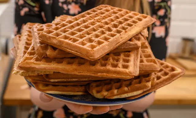 Une pile de gaufres dorées, prêtes à être dégustées. La pâte à gaufres a été cuite à la perfection, créant une texture croustillante à l'extérieur et moelleuse à l'intérieur.
