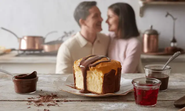 Un couple partage un moment tendre en cuisine, devant un gâteau marbré arrosé de chocolat. Une recette barquette chocolat parfaite pour un moment gourmand.