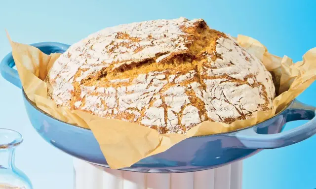 Pain maison doré dans une cocotte bleue, prêt à être dégusté. Le temps de cuisson pain 500g est parfait pour cette croûte craquelée.