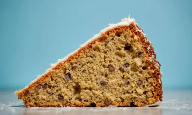 Tranche de gâteau au froment, parsemée de pépites de chocolat, avec un glaçage blanc. Un délice !
