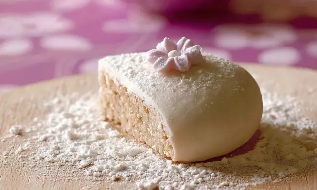 Gâteau recouvert de pâte à sucre, saupoudré de sucre glace. Une petite fleur en pâte à sucre décore le dessus. Parfait pour une recette de pâte à sucre.
