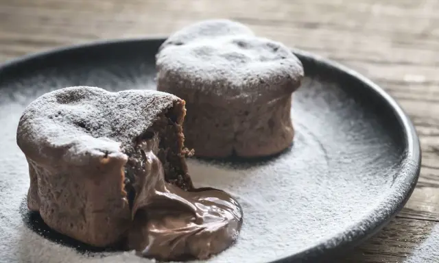 Deux coulants au chocolat inratables, saupoudrés de sucre glace, avec un cœur fondant qui déborde sur l'assiette.