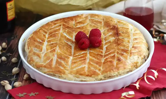 Une délicieuse galette pistache framboise dorée, décorée de fruits rouges frais, prête à être dégustée.