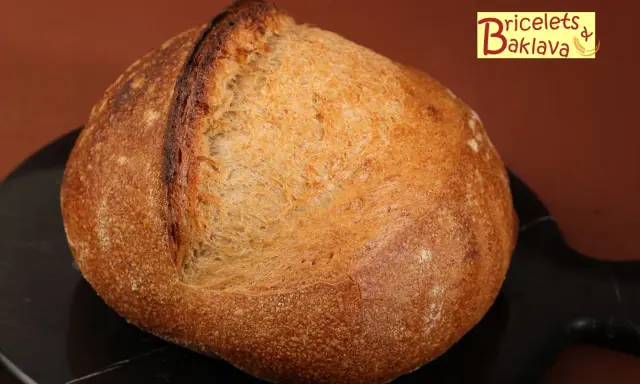 Belle miche de pain artisanal, prête après son temps de repos maximum. La croûte dorée et craquelée promet un délice.