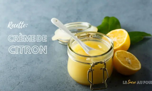 Une recette de crème au citron rapide, prête à être dégustée. Un pot en verre rempli de cette crème onctueuse, avec des citrons frais et des feuilles vertes.