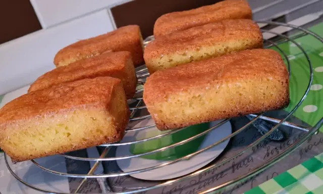 Six financiers dorés, des quatre quarts sans œuf, refroidissent sur une grille.