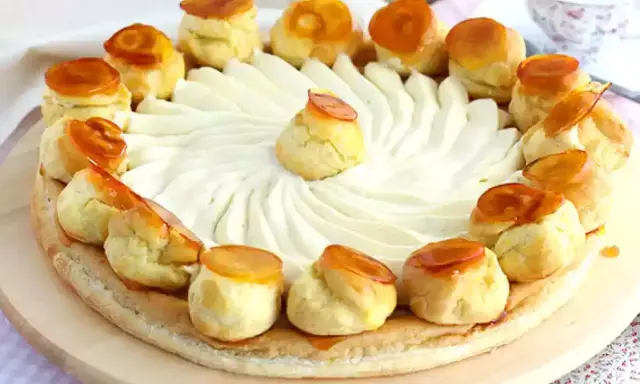 Un magnifique gâteau Saint-Honoré, orné de choux caramélisés et d'une crème onctueuse, prêt à être dégusté.