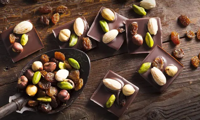 Carrés de chocolat noir Callebaut garnis d'amandes, noisettes, pistaches et raisins secs. Un délice à déguster !