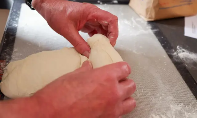 Mains travaillant la pâte à pain, étape d'autolyse. La pâte est souple et prête à être façonnée.