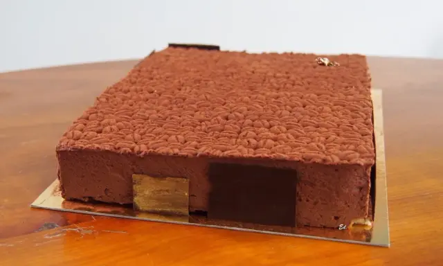 Gâteau rectangulaire au chocolat, décoré d'une texture rappelant des grains de café. Une recette insert crémeux café qui promet une dégustation exquise.