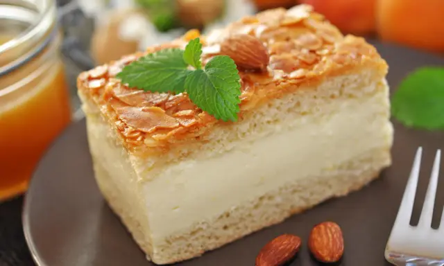 Gâteau nid d'abeille, une part crémeuse garnie d'amandes effilées et d'une touche de menthe. Parfait pour une recette gourmande.