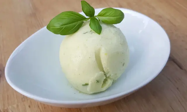 Une boule de sorbet citron vert et basilic, parfaite pour une recette sorbet citron professionnel. Délicatement garnie de feuilles de basilic frais.