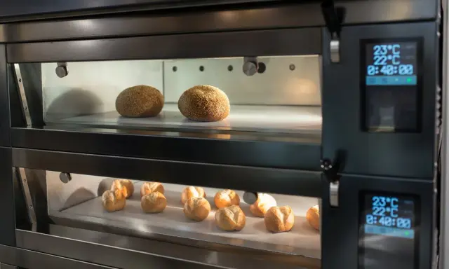 Deux étages de pains dorés dans un four professionnel. La fonction étuve four assure une cuisson parfaite.