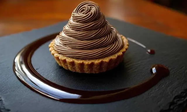 Délicieux Mont Blanc au chocolat, une recette gourmande à essayer. La crème onctueuse forme un cône parfait sur la tartelette.