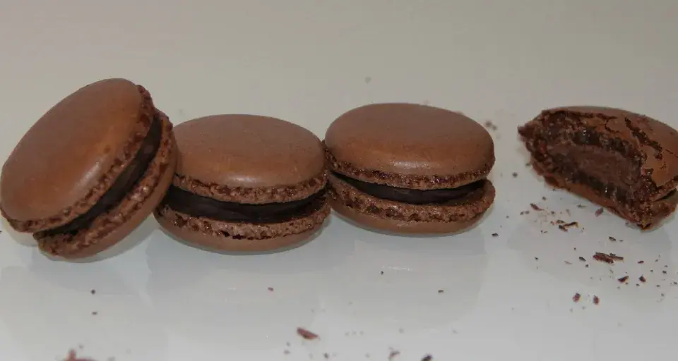 Trois macarons au chocolat et un croqué, parfaits pour une recette macaron chocolat.