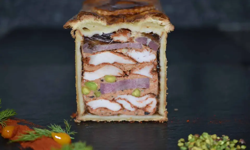 Pâté en croûte aux multiples couches de viandes, pistaches et gelée. Une œuvre d'art culinaire digne de la recette du meilleur pâté en croûte du monde.