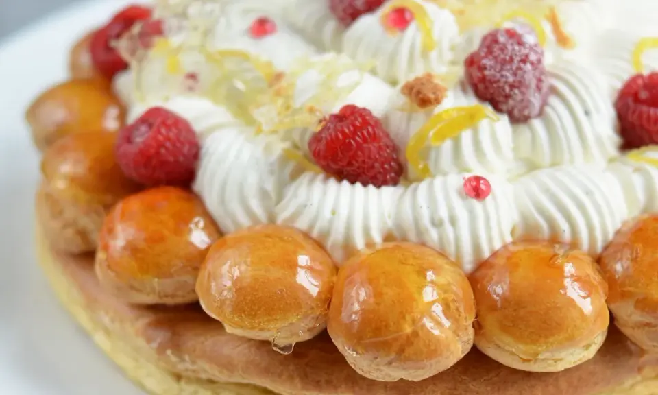 Un déliceux saint honoré framboise, orné de crème fouettée, de fruits rouges et de petites brioches caramélisées.