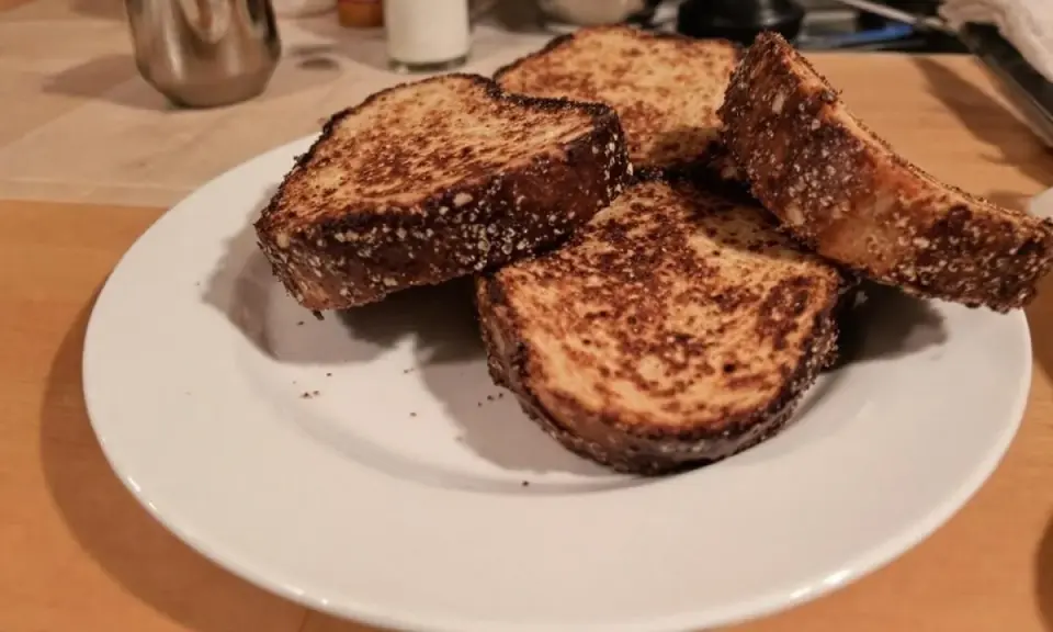 Quatre tranches de pain dur au four, dorées et croustillantes, sur une assiette blanche.
