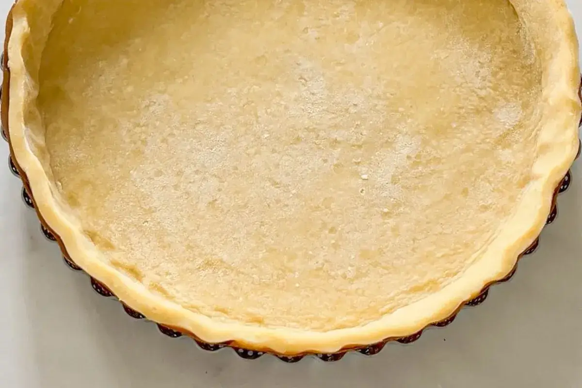 Une tartelette prête à être garnie, avec une belle pâte brisée à l'ancienne, dorée et légèrement farinée.